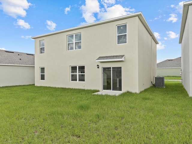 back of property featuring central AC unit and a lawn