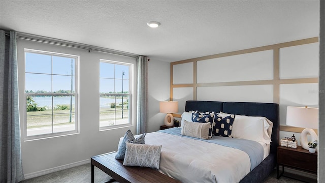 carpeted bedroom with a water view and a textured ceiling