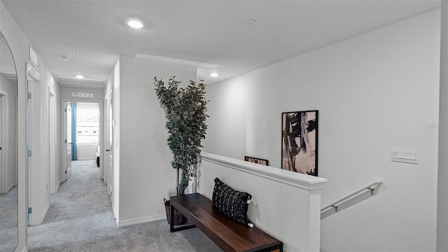 hallway featuring a textured ceiling and light colored carpet