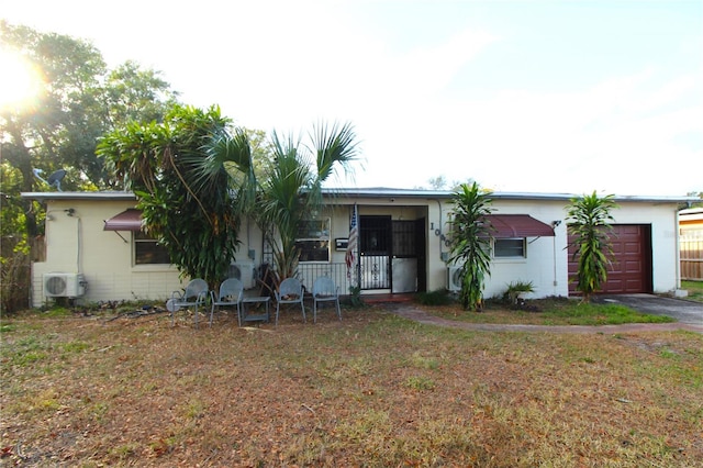 view of front facade with covered porch, ac unit, a garage, and a front lawn