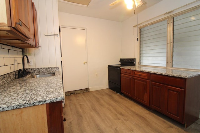 kitchen with tasteful backsplash, baseboards, light wood-style flooring, black electric range, and a sink