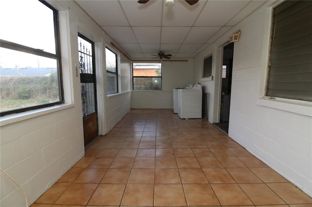 hallway featuring a paneled ceiling, light tile patterned flooring, and washer and clothes dryer