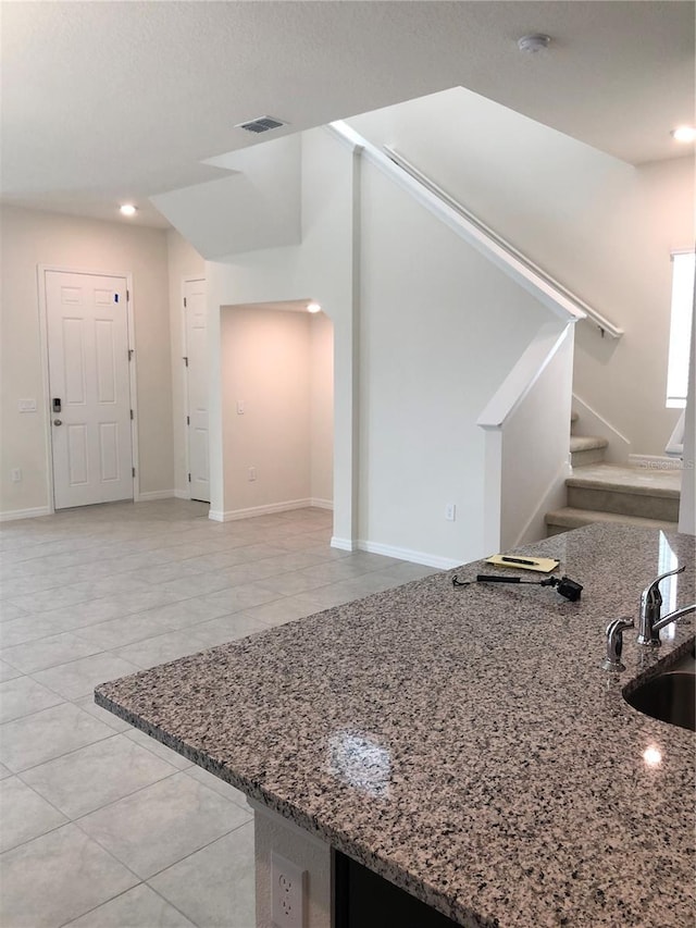 kitchen with stone counters, sink, and light tile patterned floors