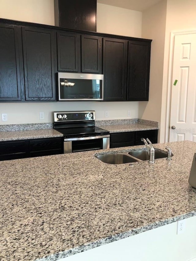 kitchen with stainless steel appliances, light stone counters, and sink