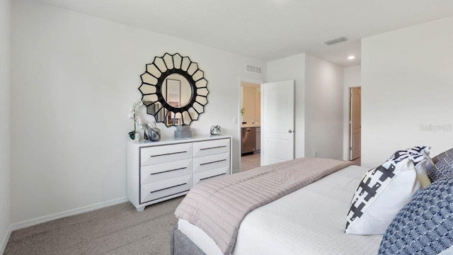 bedroom featuring ensuite bathroom and light colored carpet