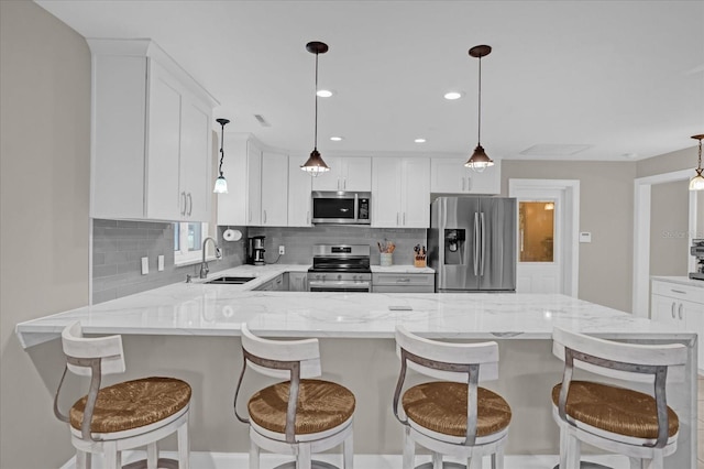 kitchen with white cabinets, sink, light stone countertops, appliances with stainless steel finishes, and decorative light fixtures