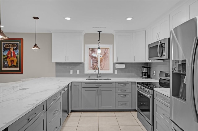 kitchen with white cabinetry, sink, stainless steel appliances, and decorative light fixtures