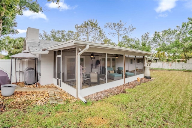 rear view of property featuring a gazebo, a sunroom, a yard, and ceiling fan