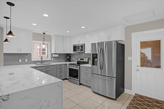 kitchen with light stone countertops, decorative light fixtures, stainless steel appliances, and white cabinets