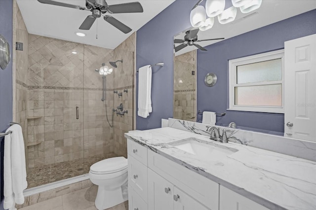 bathroom with ceiling fan, tile patterned flooring, vanity, a shower with shower door, and toilet