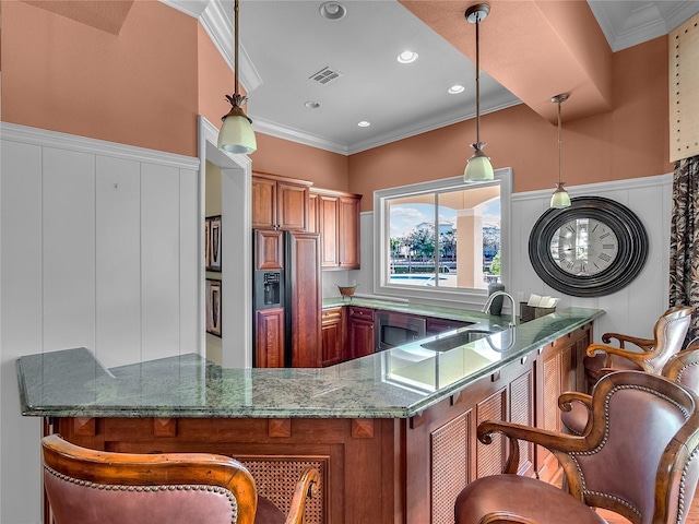 kitchen with hanging light fixtures, crown molding, sink, and a breakfast bar area