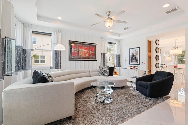 living room with crown molding, a tray ceiling, and tile patterned flooring