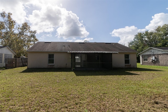 rear view of house featuring a yard and a sunroom