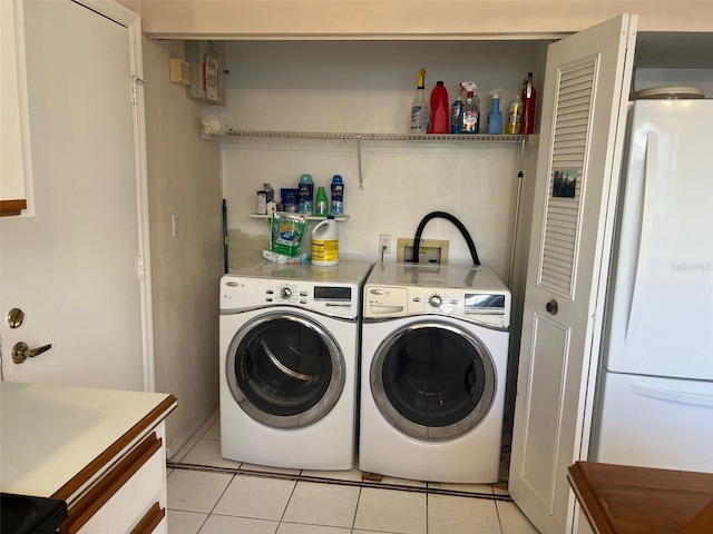 clothes washing area with light tile patterned floors and washer and clothes dryer