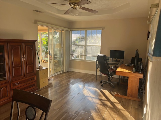 home office with a tray ceiling, ceiling fan, and wood-type flooring