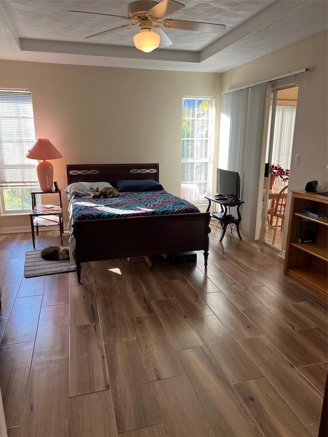 bedroom featuring hardwood / wood-style flooring, ceiling fan, and multiple windows