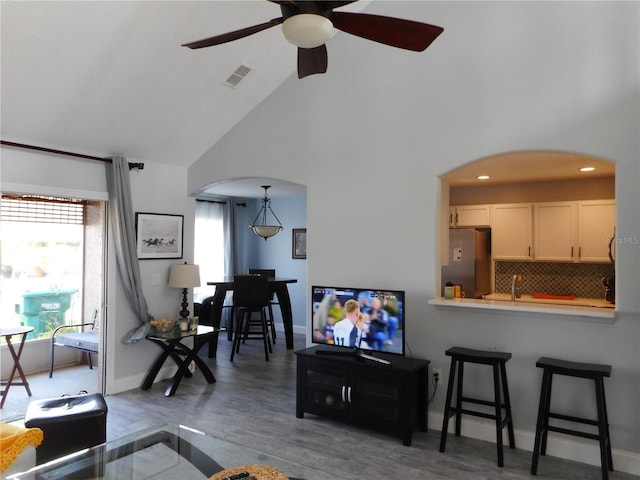 living room with dark hardwood / wood-style flooring, high vaulted ceiling, and ceiling fan