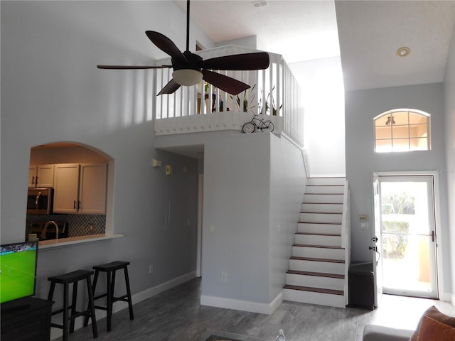 interior space featuring ceiling fan, a towering ceiling, and dark wood-type flooring