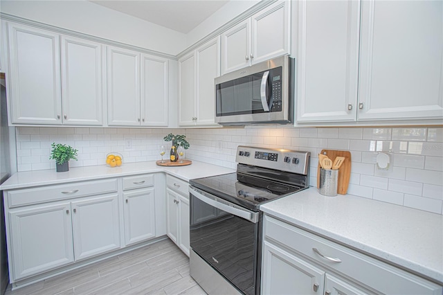 kitchen featuring white cabinets, backsplash, and appliances with stainless steel finishes