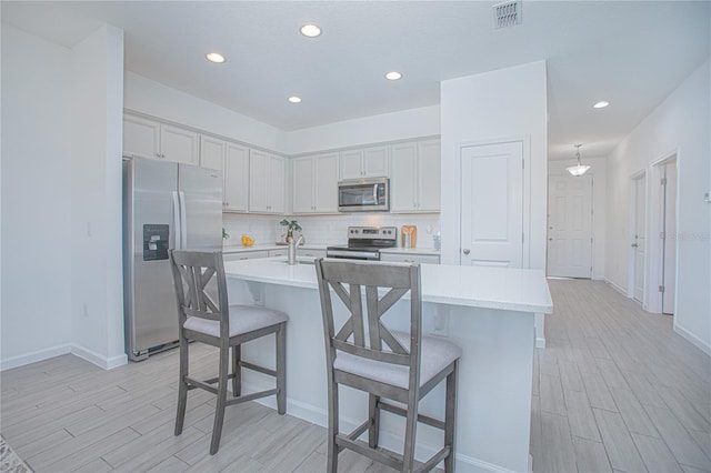 kitchen with a kitchen bar, appliances with stainless steel finishes, and an island with sink