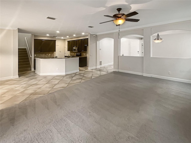 unfurnished living room featuring light colored carpet, ceiling fan, and ornamental molding