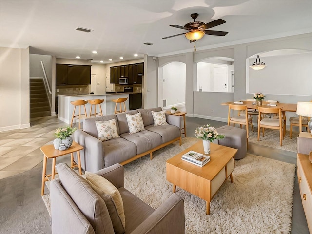 tiled living room with ceiling fan and ornamental molding