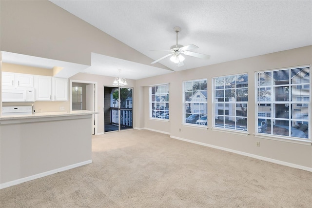 unfurnished living room featuring ceiling fan with notable chandelier, light colored carpet, lofted ceiling, and a textured ceiling