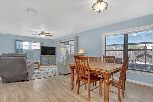 dining room featuring a textured ceiling, ceiling fan, and light hardwood / wood-style flooring