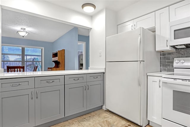 kitchen with white appliances, a textured ceiling, tasteful backsplash, gray cabinets, and white cabinets