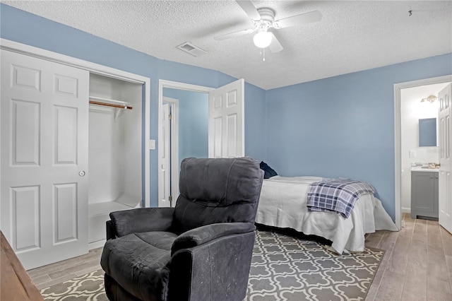 bedroom featuring ensuite bath, a closet, ceiling fan, and a textured ceiling