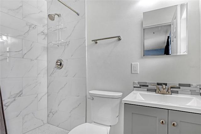 bathroom with tiled shower, vanity, and toilet