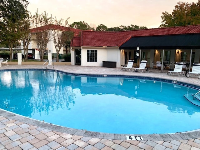 pool at dusk with a patio area