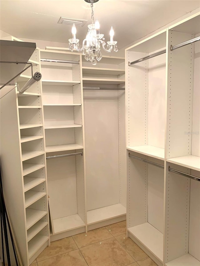 walk in closet featuring a notable chandelier and light tile patterned flooring