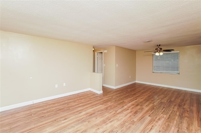 spare room with ceiling fan, a textured ceiling, and light wood-type flooring