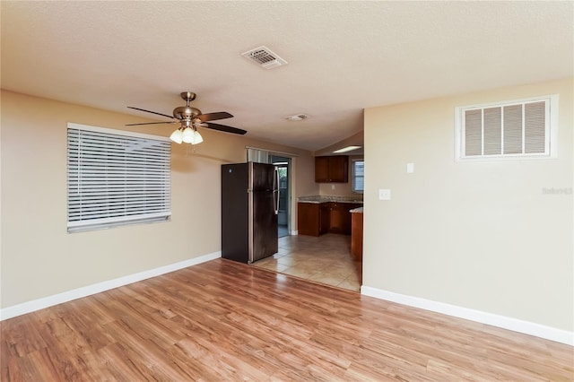 interior space with vaulted ceiling, ceiling fan, light hardwood / wood-style flooring, and a textured ceiling