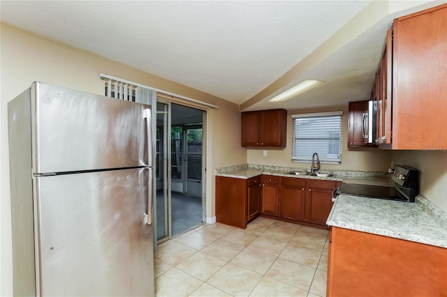 kitchen featuring sink, light tile patterned floors, stainless steel appliances, and a textured ceiling