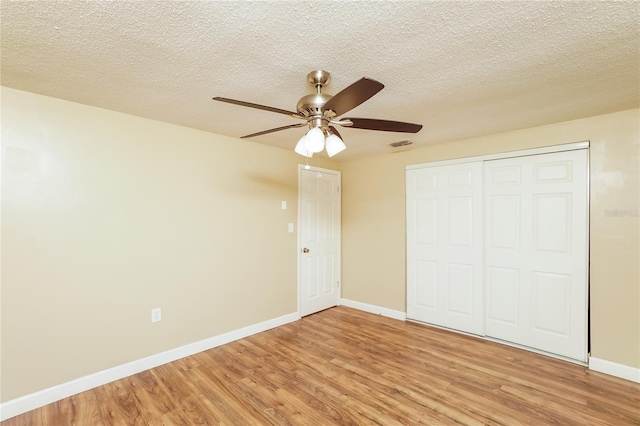 unfurnished bedroom with hardwood / wood-style floors, ceiling fan, a textured ceiling, and a closet