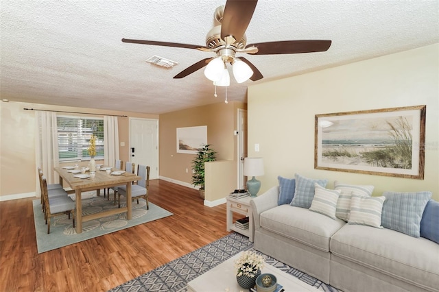 living room featuring a textured ceiling, hardwood / wood-style flooring, and ceiling fan