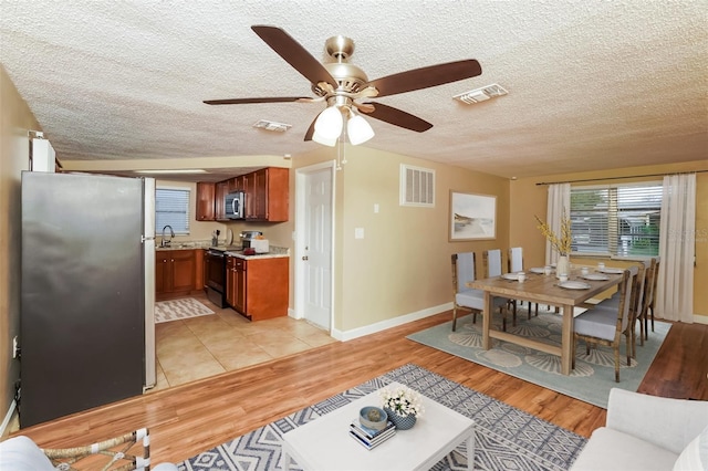 living room featuring ceiling fan, light hardwood / wood-style flooring, a textured ceiling, and sink