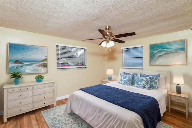 bedroom with ceiling fan, light hardwood / wood-style floors, and a textured ceiling