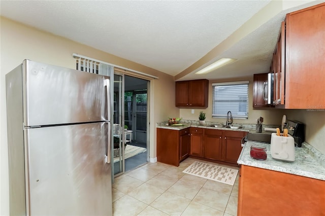 kitchen with light tile patterned flooring, a textured ceiling, stainless steel appliances, and sink