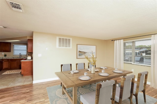 dining area featuring a textured ceiling, light hardwood / wood-style floors, and sink