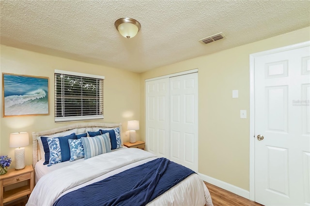 bedroom with wood-type flooring, a textured ceiling, and a closet