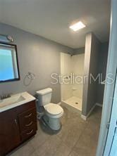 bathroom with a shower stall, toilet, and vanity