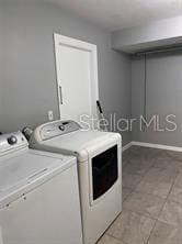 washroom featuring washer and dryer, baseboards, laundry area, and light tile patterned floors