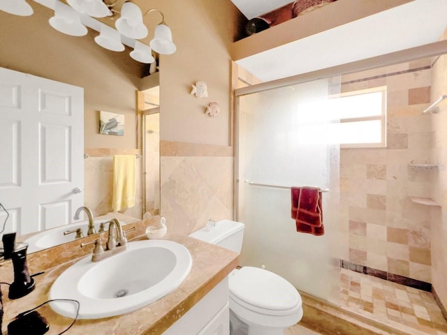 bathroom featuring vanity, a shower with shower door, tile walls, and toilet