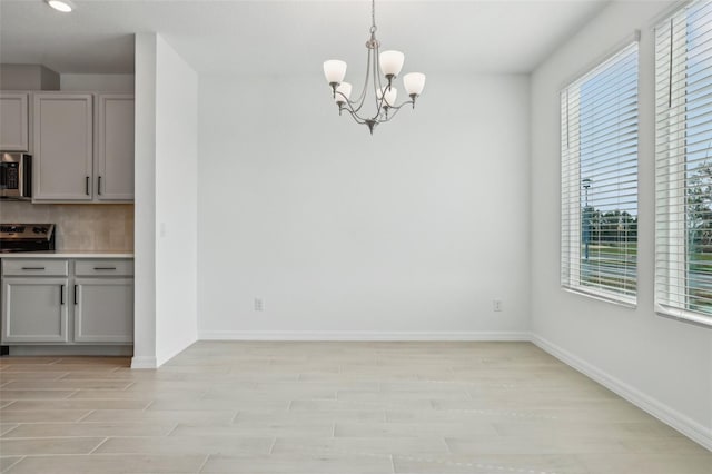 unfurnished dining area featuring a notable chandelier and light wood-type flooring