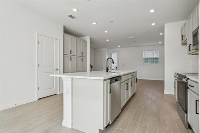 kitchen featuring stainless steel appliances, sink, and a kitchen island with sink