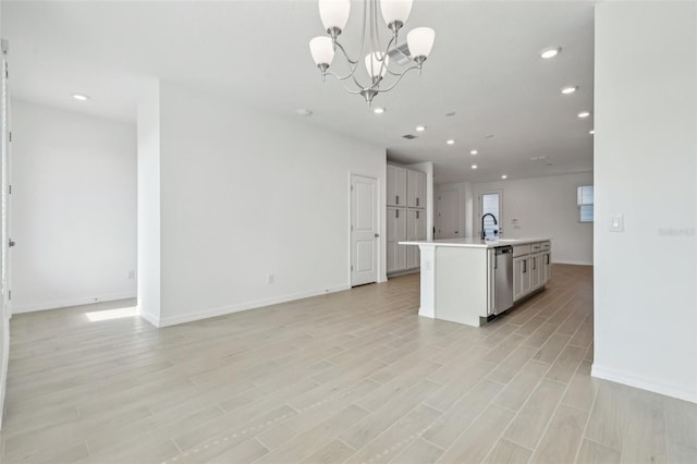 kitchen with light hardwood / wood-style flooring, a notable chandelier, an island with sink, decorative light fixtures, and stainless steel dishwasher