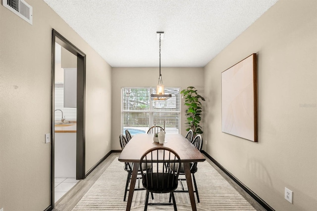 dining space with sink, a textured ceiling, and light hardwood / wood-style flooring